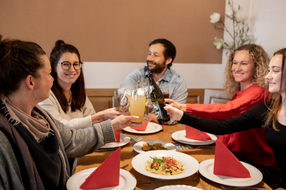 Gäste stoßen an und genießen den Mittagstisch in der Germania